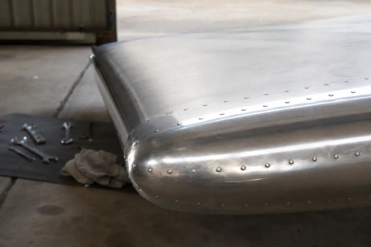 Bord d’attaque d’une aile de monomoteur dans un hangar, outillage posé au sol